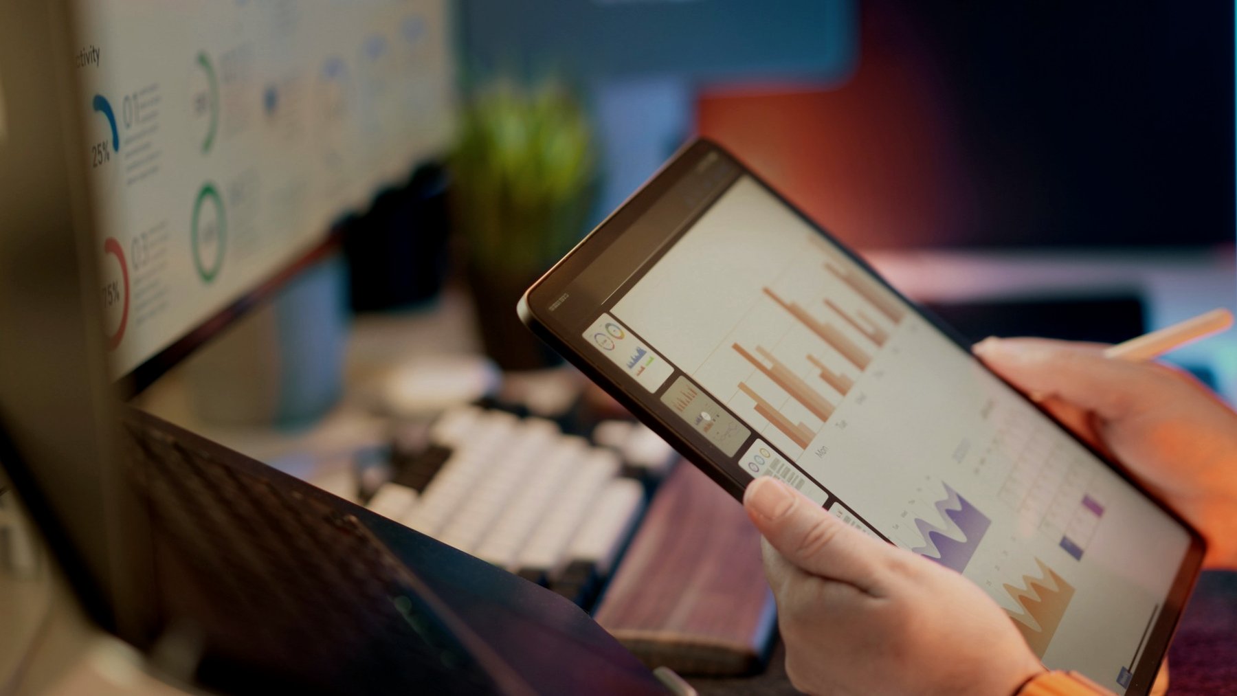 A hand holding a tablet showing bar charts
